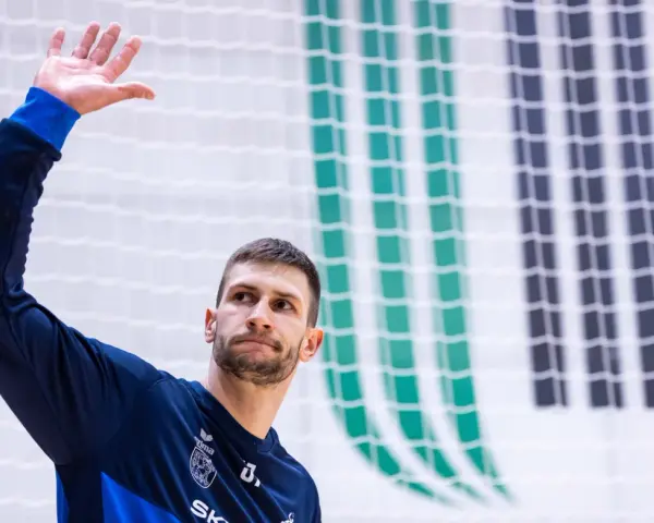 Michał Przybylak wita kibiców, unosząc dłoń.
