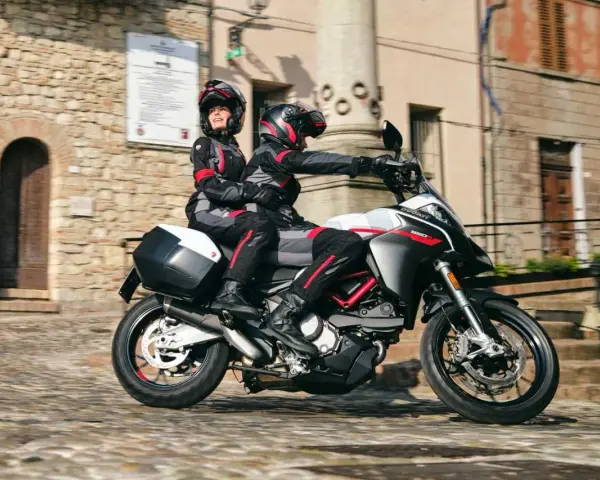 Para jadąca na sportowym motocyklu Ducati przez urokliwe, brukowane uliczki.