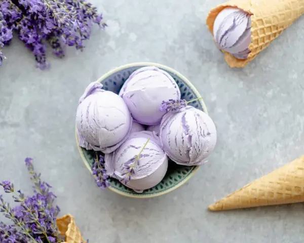 Schalen und Waffelkegel mit cremigem Lavendeleis, garniert mit frischen Lavendelzweigen.