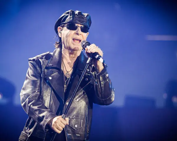 Klaus Meine, jung und rockig, singt ins Mikrofon, trägt Lederjacke und Kappe.