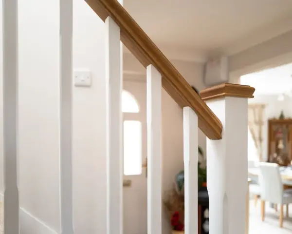 Barandilla de escalera blanca con pasamanos de madera, ideal para saber como modernizar una barandilla de madera.