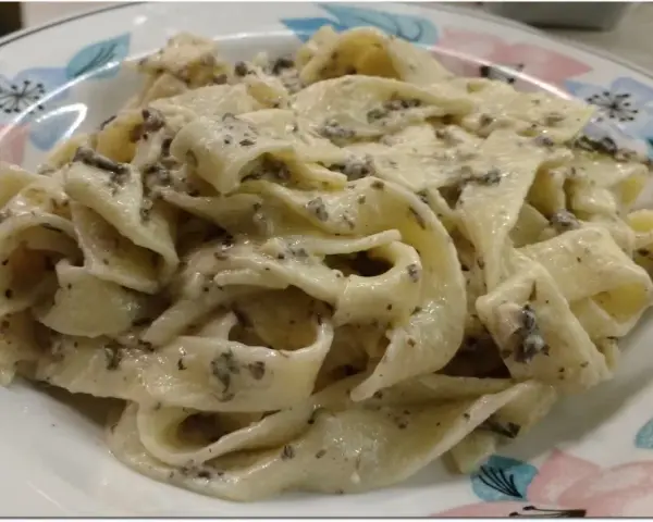 Pappardelle z kremowym sosem z mascarpone i aromatyczną pastą truflową, podane na talerzu z kwiatowym wzorem.