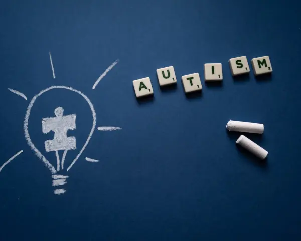 Żarówka z symbolem puzzli i litery tworzące słowo AUTISM. Wiele sławnych osób z autyzmem inspiruje nas każdego dnia.