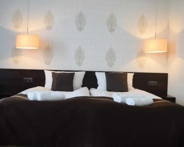 Przytulny pokój hotelowy z podwójnym łóżkiem, białymi ręcznikami i lampami. Czy można wynająć pokój w hotelu mając 17 lat?