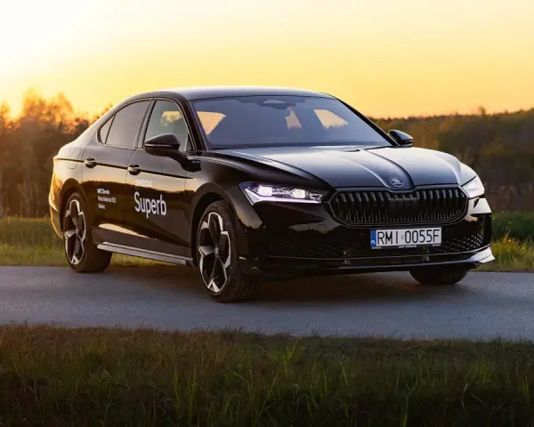 Czarny Skoda Superb 4 na tle zachodzącego słońca. Elegancki sedan z nowoczesnymi światłami i felgami.