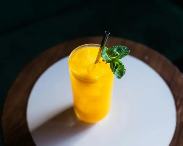 Orzeźwiający koktajl z mango, z lodem i listkami mięty, podany w szklance ze słomką.