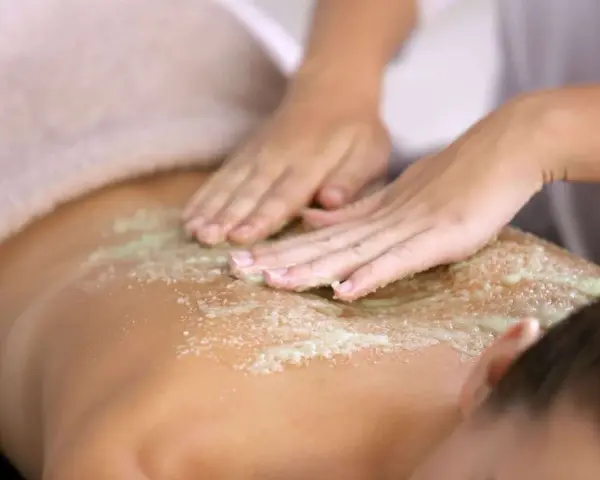 Manos expertas realizan un peeling corporal exfoliante, dejando la piel suave y renovada.