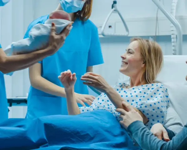 Szczęśliwi rodzice odbierają noworodka od położnej. Nauka i praktyka w najlepszym wydaniu, tworzą rodzinę.
