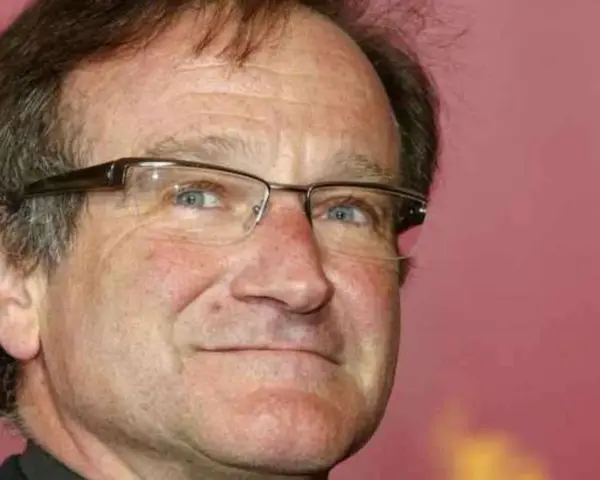 Primo piano di Robin Williams con occhiali, un uomo che ha portato gioia a molti, anche se il suo figlio morto non ha potuto vederlo.