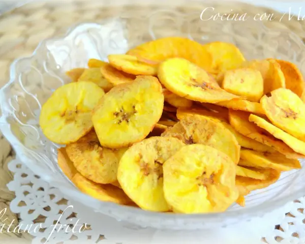 Crujientes rodajas de plátano frito doradas, servidas en un cuenco de cristal. Un delicioso snack casero.