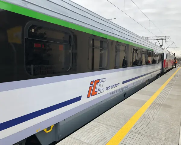 Pociąg PKP Intercity z charakterystycznym logo eic a ic stoi na peronie.