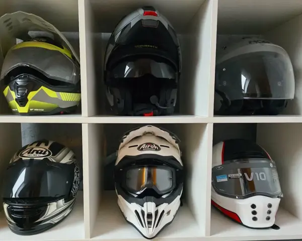 Różne rodzaje kasków motocyklowych: szczękowy, integralny, enduro i crossowy. Kolekcja na półce.