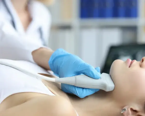 Fizjoterapeuta wykonuje badanie USG szyi, co może być częścią terapii stawu skroniowo-żuchwowego.