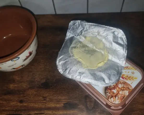 Opakowanie po maśle, które właśnie zostało zużyte, leży obok miseczki z pieskami. Gdzie wyrzucić opakowanie po maśle?