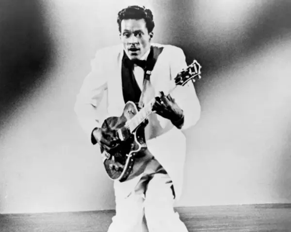 Chuck Berry in weißem Anzug spielt Gitarre, bereit für "Johnny B. Goode".