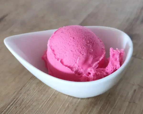 Ein Löffel leuchtend pinkes Eis in einer weißen Schale. Vielleicht ist das die Antwort auf die Frage, warum es kein Kirscheis gibt – weil dieses hier so gut ist!