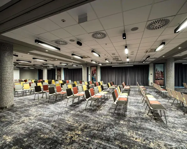 Sala konferencyjna w hotelu Mercure Wrocław, przygotowana na wydarzenie. Rzędy kolorowych krzeseł czekają na gości.
