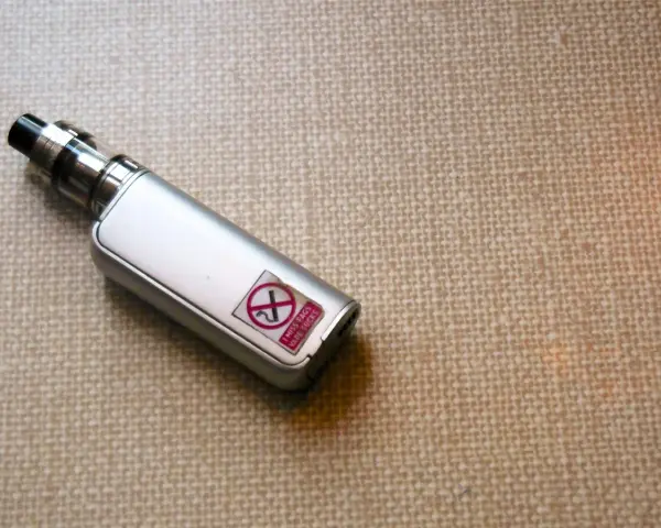 Un vape plateado con una pegatina que dice "I MISS FAGS VAPE SUCKS" y un símbolo de prohibido.