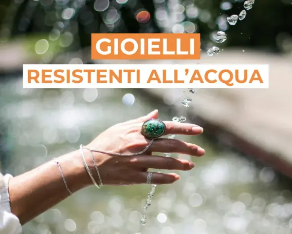 Mano adornata con gioielli che non si rovinano con l'acqua, sotto un getto d'acqua scintillante.