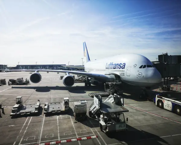Lufthansa A380 na płycie lotniska we Frankfurcie. W tle widać inne samoloty i budynki terminali, typowe dla lotnisk w Niemczech.