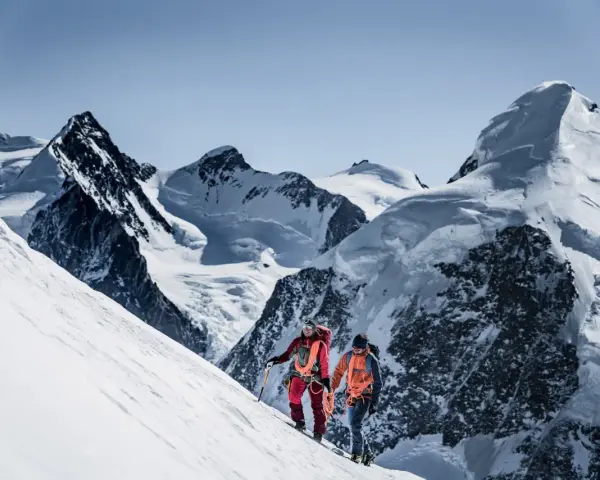 Zwei Bergsteiger, ein beal escaper-Team, steigen einen schneebedeckten Hang hinauf, umgeben von majestätischen, eisigen Gipfeln.
