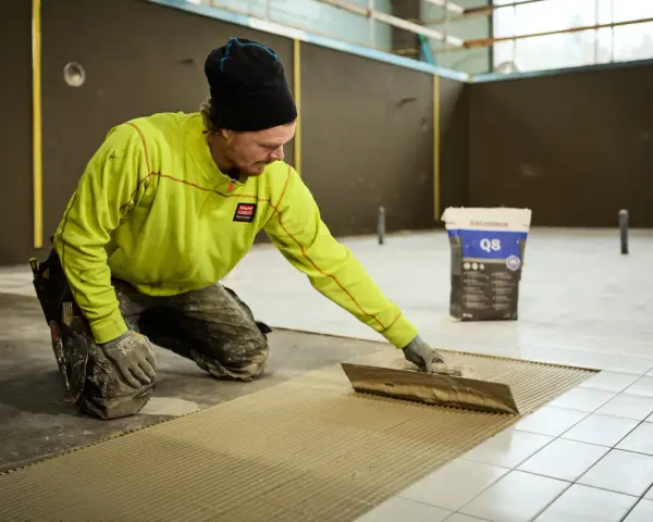 Man i gul jacka lägger fix på golvet för att byta ut det.