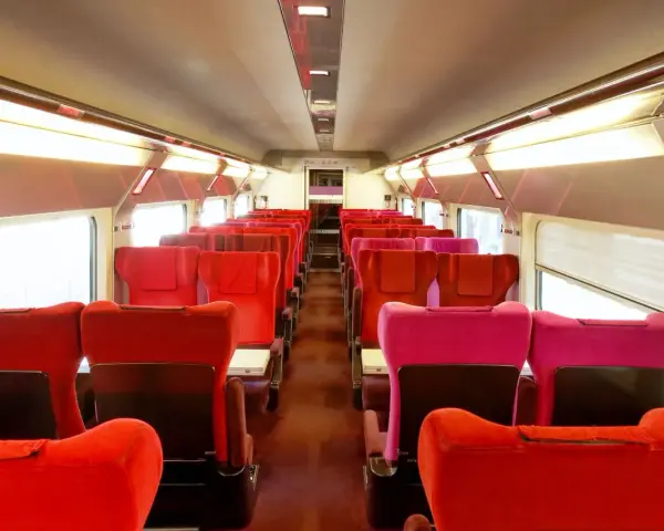 Rows of red and pink seats inside a train car, ready for passengers on the best train from Amsterdam to Paris.