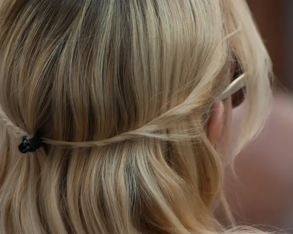 Piaskowy blond włosów spięty warkoczem z tyłu głowy. Delikatne pasma opadają na ramiona.