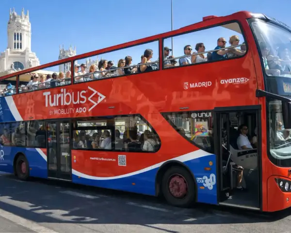Tourists enjoy a hop on hop off bus tour of Madrid, Spain, with the iconic Turibus double-decker bus.