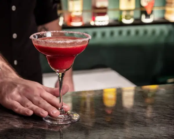 Margarita przepis: orzeźwiający, czerwony drink z solą na brzegu kieliszka, podawany przez barmana.