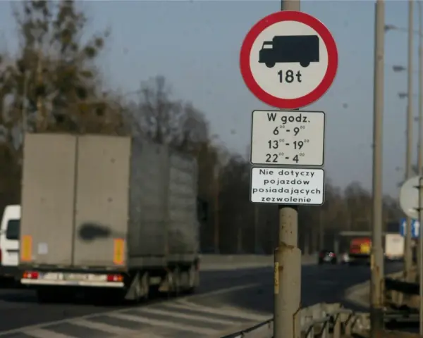 Znak zakazu wjazdu dla ciężarówek powyżej 18t w określonych godzinach. Czy ciężarówki mogą jeździć w niedzielę? Ten znak wyjaśnia ograniczenia.