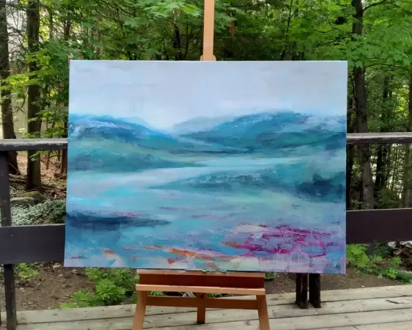 Un paysage abstrait aux teintes bleues et vertes, évoquant des montagnes brumeuses et un lac. Le fond de tableau peinture est posé sur un chevalet, en extérieur, entouré de verdure.