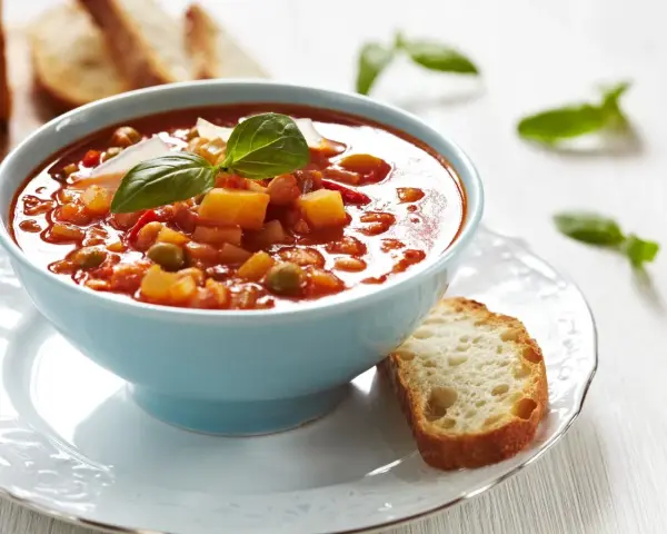 Aksamitna zupa solferino w błękitnej miseczce, ozdobiona bazylią i parmezanem, podana z chrupiącą grzanką.
