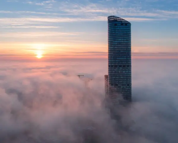 Sky Tower Wrocław, jego imponująca wysokość ginie we mgle o wschodzie słońca. Widok zapiera dech.