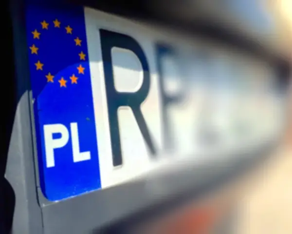 Zbliżenie na polską tablicę rejestracyjną z symbolem UE. Litery "PL" i fragment numeru rejestracyjnego są wyraźne.