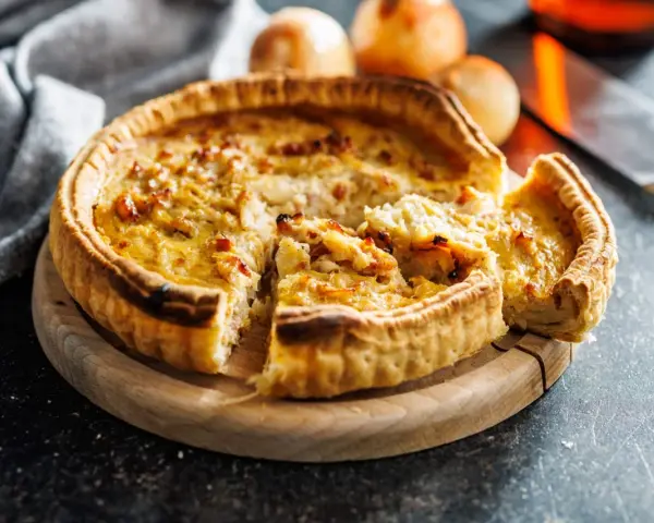 Une quiche lorraine dorée, prête à être dégustée. La cuisson est parfaite, la pâte croustillante et la garniture onctueuse.