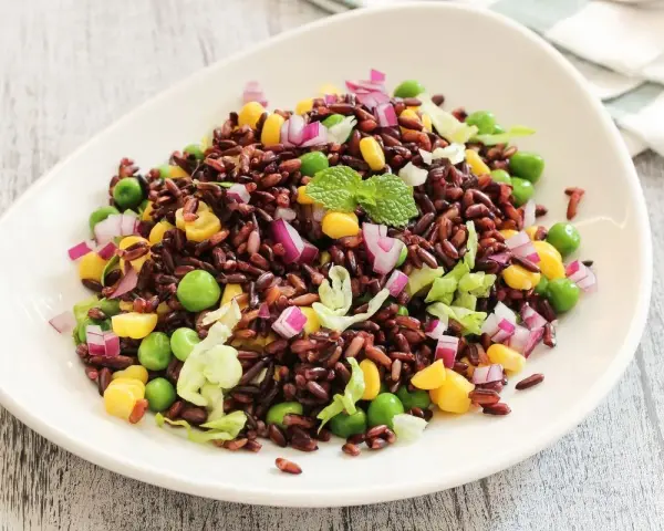Insalata colorata con riso venere, piselli, mais, cipolla rossa e lattuga. Un'idea fresca per le tue riso venere ricette.