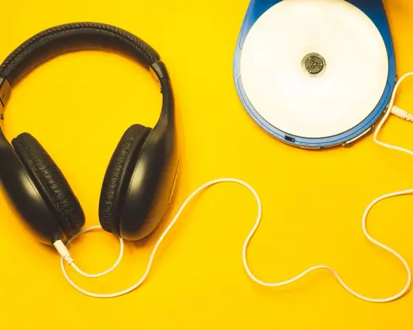 Kopfhörer und ein Discman auf gelbem Hintergrund. Perfekt, um neue Musik zu promoten und den Sound zu genießen.