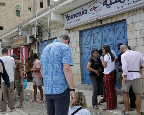 Ludzie stoją przed biurem Yemenia Airways. Czy Jemen jest bezpieczny? To pytanie zadają sobie podróżni, obserwując codzienne życie w tym kraju.