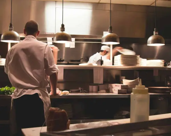 Kucharz w białej koszuli i fartuchu pracuje w kuchni restauracyjnej. To idealne miejsce, by napisać list motywacyjny kucharz.