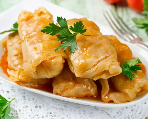 Talerz gołąbków w sosie, udekorowany natką pietruszki. Zastanawiasz się, ile kcal ma gołąbek?