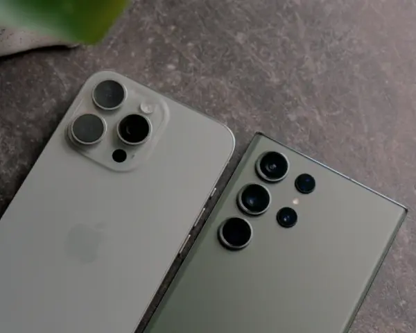 Dwa najnowsze fotosmartfony, iPhone i Samsung, leżą obok siebie na ciemnym tle.