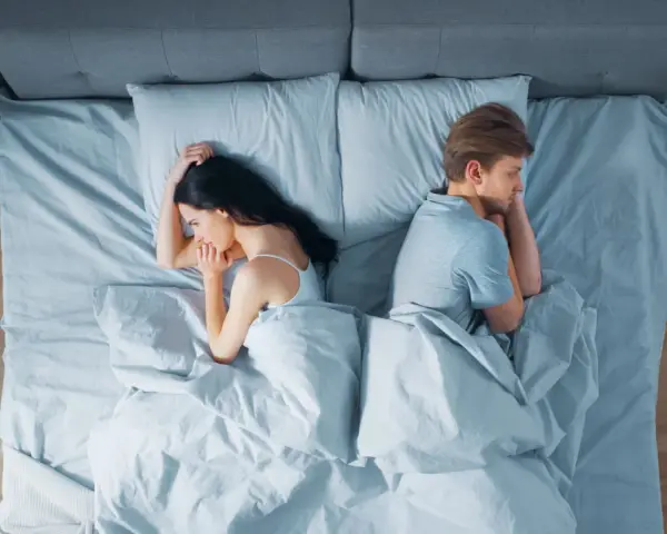 Ein Paar liegt im Bett, jeder auf seiner Seite, die Rücken einander zugewandt. Getrennte Schlafzimmer – der Anfang vom Ende?