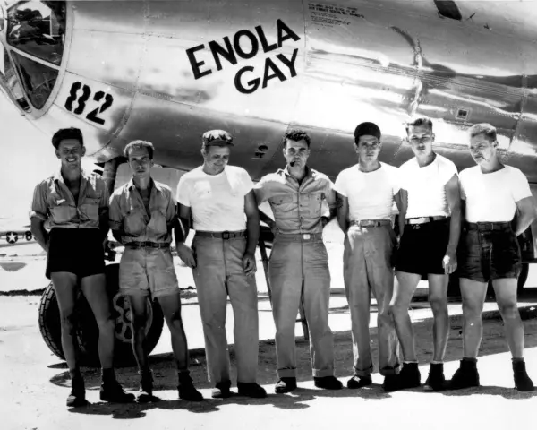 Siedmiu mężczyzn pozuje przed samolotem B-29 o nazwie "Enola Gay".