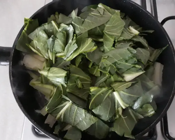 Verdure a coste in padella, che rilasciano vapore mentre cuociono.