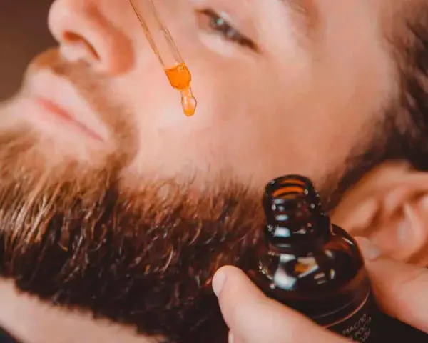Un hombre aplica aceite con un gotero a su barba. Un secreto para tener una barba bonita y cuidada.