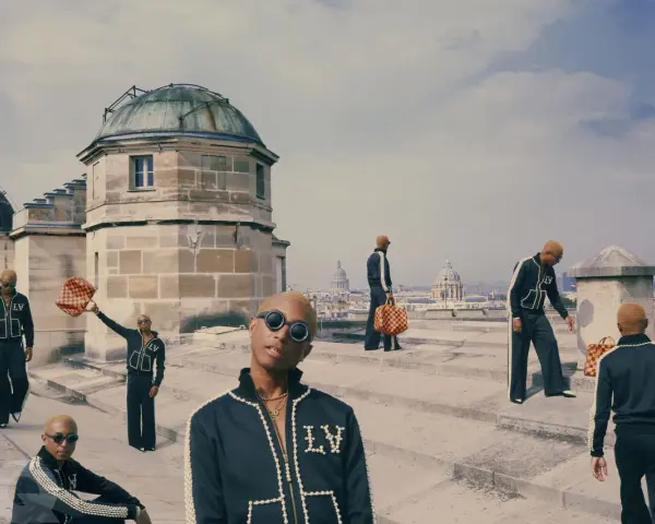 Uomini con tute Louis Vuitton e borse iconiche, un omaggio a chi era Louis Vuitton e al suo impero.