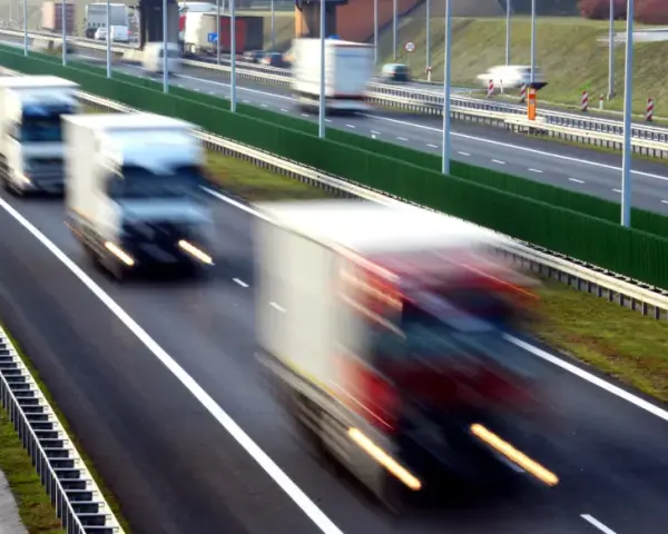 Ciężarówki na autostradzie, rozmyte przez ruch. Kierowcy potrzebują pauzy, by odpocząć od długiej jazdy.