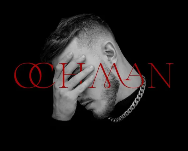 Krystian Ochman - nowa płyta. Artysta z dłonią na twarzy, w tle czerwony napis "OCHMAN".