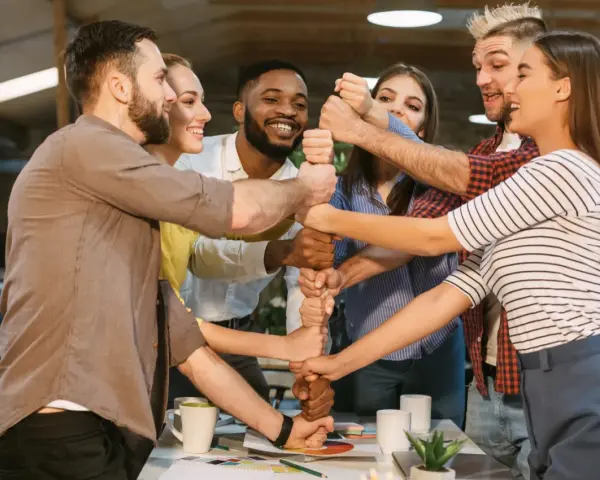 Une équipe soudée, poings serrés, symbolisant l'unité et la collaboration. Une belle idée séminaire pour renforcer la cohésion.